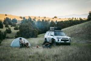 Two Men Camping in the Forest with a GOBI Racks Roof Rack Carrying Supplies on a Silver Toyota 4Runner