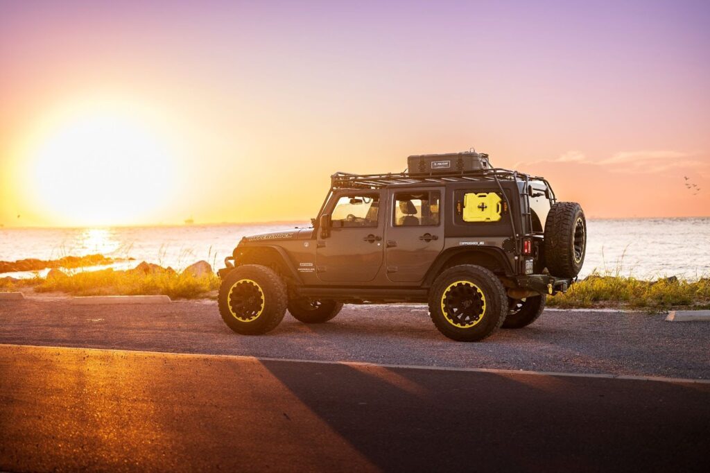 Choosing the Best Car Top Cargo Carrier for Extra Storage | GOBI Racks A GOBI Racks Roof Rack On Top of a Jeep Wrangler Driving at Sunset